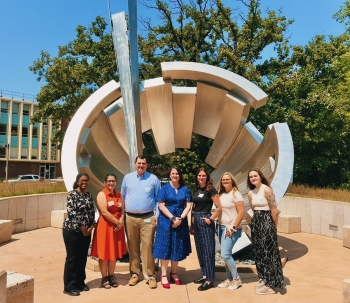 Group photo by one of the University's outdoor sculptures