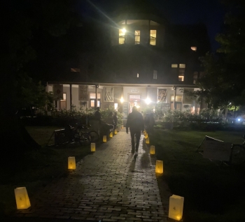 View of homemade paper lanterns lighting up both sides of a walkway outside a Chautauqua building at night