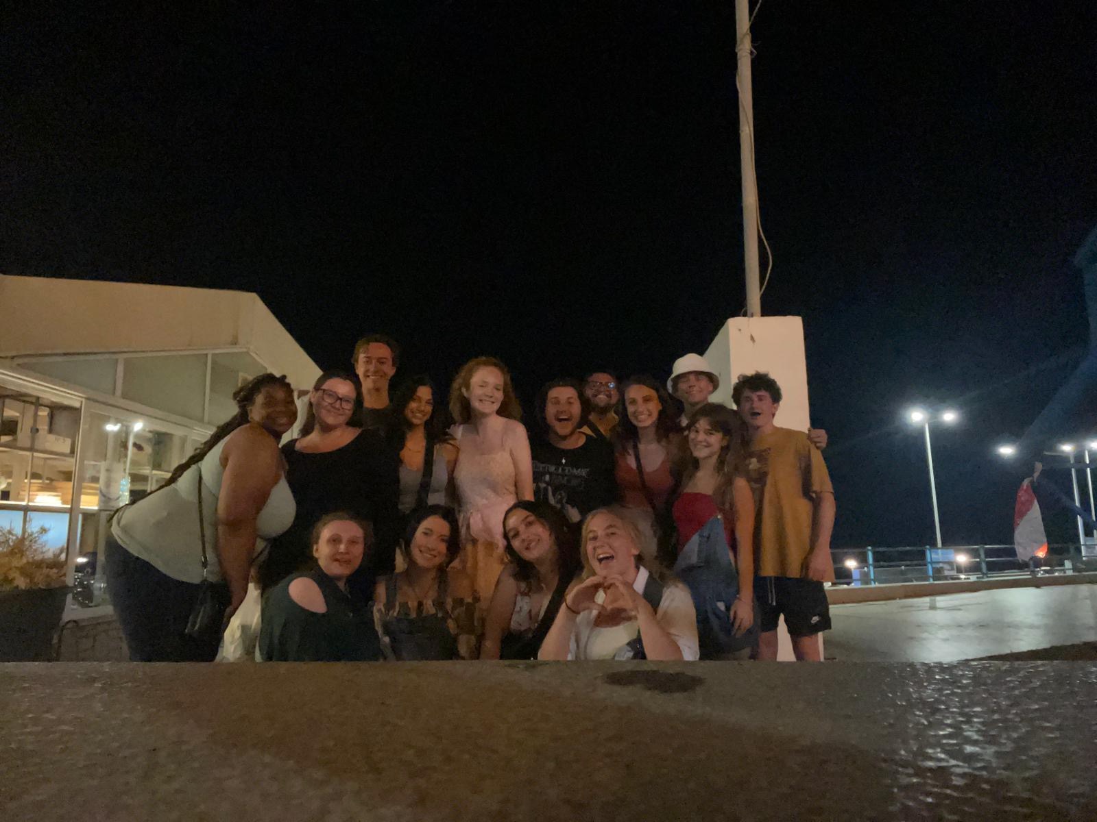 An outdoor group photo of 15 people taken at night