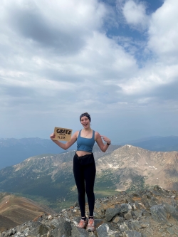 Photo of Cameron posing with a sign that labels Grays Peak and its summit height