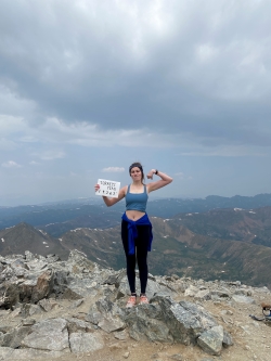 Photo of Cameron holding a sign labeling Torreys Peak and the height of its summit