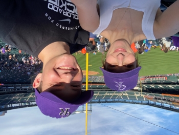 Selfie of Cameron and Kaden at a baseball game. The two are wearing matching baseball caps.