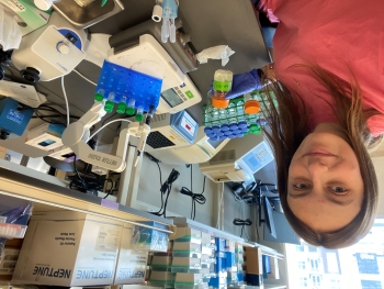 Cameron sits at a lab bench with lots of laboratory equipment.