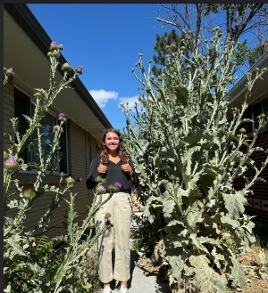 Ella standing amongst gigantic thistle plants that are taller than she is, and she's a volleyball player!