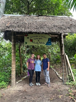 Emma, Alexi, and Javier stand in front of the sign Emma and Alexi designed for the entrance to the Sendero.