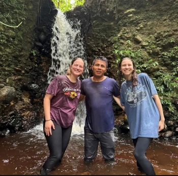 Emma, Alexi, and Javier pose in front of a waterfall, having just walked through for the naming ceremony.