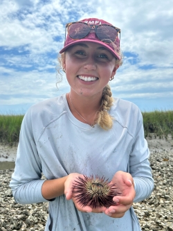 Emma smiles and holds some kind of poofy organism in her hands