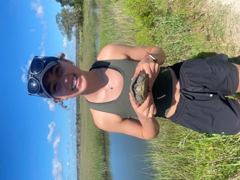 Emma stands smiling and holding a small turtle.