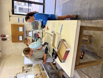 Emma and two other interns stand over a lab table, various tools and trays on the table. These three interns appear to be dissecting fish.