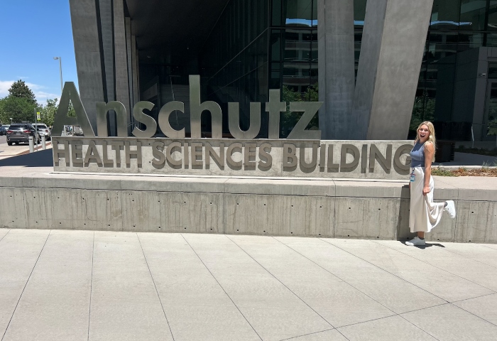 Josalin posing in from of the Anschutz Health Sciences Building sign