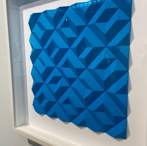 Diagonal view of a large square block of blue art hung on a wall