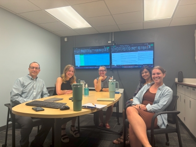 Group picture of several people in a conference room gathered around a table as if during a meeting