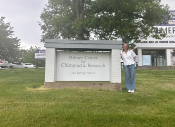 Kylie poses with the sign outside the Palmer Center for Chiropractic Research