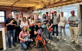 The photo shows a group of people in office attire holding a variety of different NERF guns before the office-wide NERF game begins.