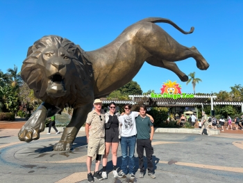 Kiana and three family members at the San Diego Zoo, posing in front of a giant bronze lion statue