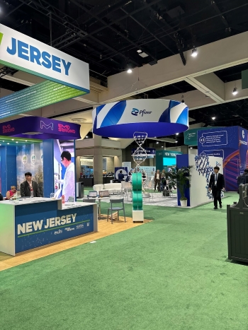 View of the green-carpeted Pfizer booth area with multiple kiosks and signs