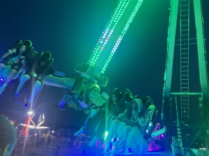 A ride at the county fair with seats that lock in riders with grip bars. It appears to swing around in the air.