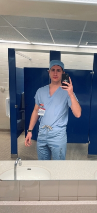 Selfie of Moodi in scrubs in a bathroom setting