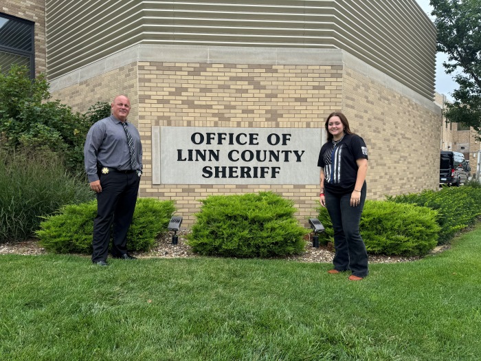 Monét poses with a law enforcement officer in front of the Linn County Sheriff's Office sign