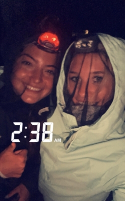 Timestamped 2:32am selfie of Anna and a friend in the dark. They are each covered head to toe in clothing and have what appears to be mosquito net over their faces