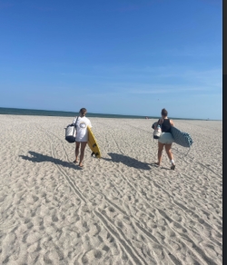 Anna and a friend haul bag chairs and other equipment across the beach