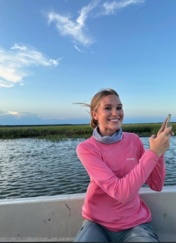 Anna smiles, sitting in a boat on the water during the daytime