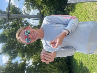 Anna wearing a light-blue long-sleeved tee and holding a fish to show the camera
