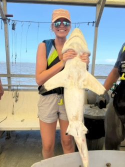 Anna holding a shark upright against the length of her body