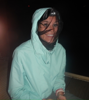 Photo of Anna nightboating. She is wearing what appears to be a mosquito net over her head and face.