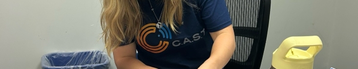 Close-up of a dark-blue T-shirt that says C.A.S.T. in yellow letters