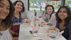 Claudia and three other interns smile on either sides of a diner table booth