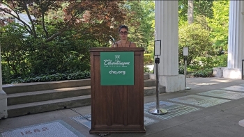 Claudia stands behind a lecturn, visible only from her neck up, speaking The lecturn contains the CHQ insignia of Chautauqua Institution.