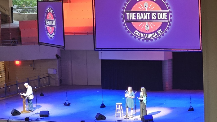 View from audience of a stage where two people are performing a comedic act.