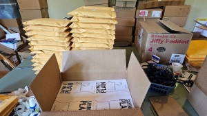 View of a mail room table with boxes, stacks of filled envelopes, and packing materials