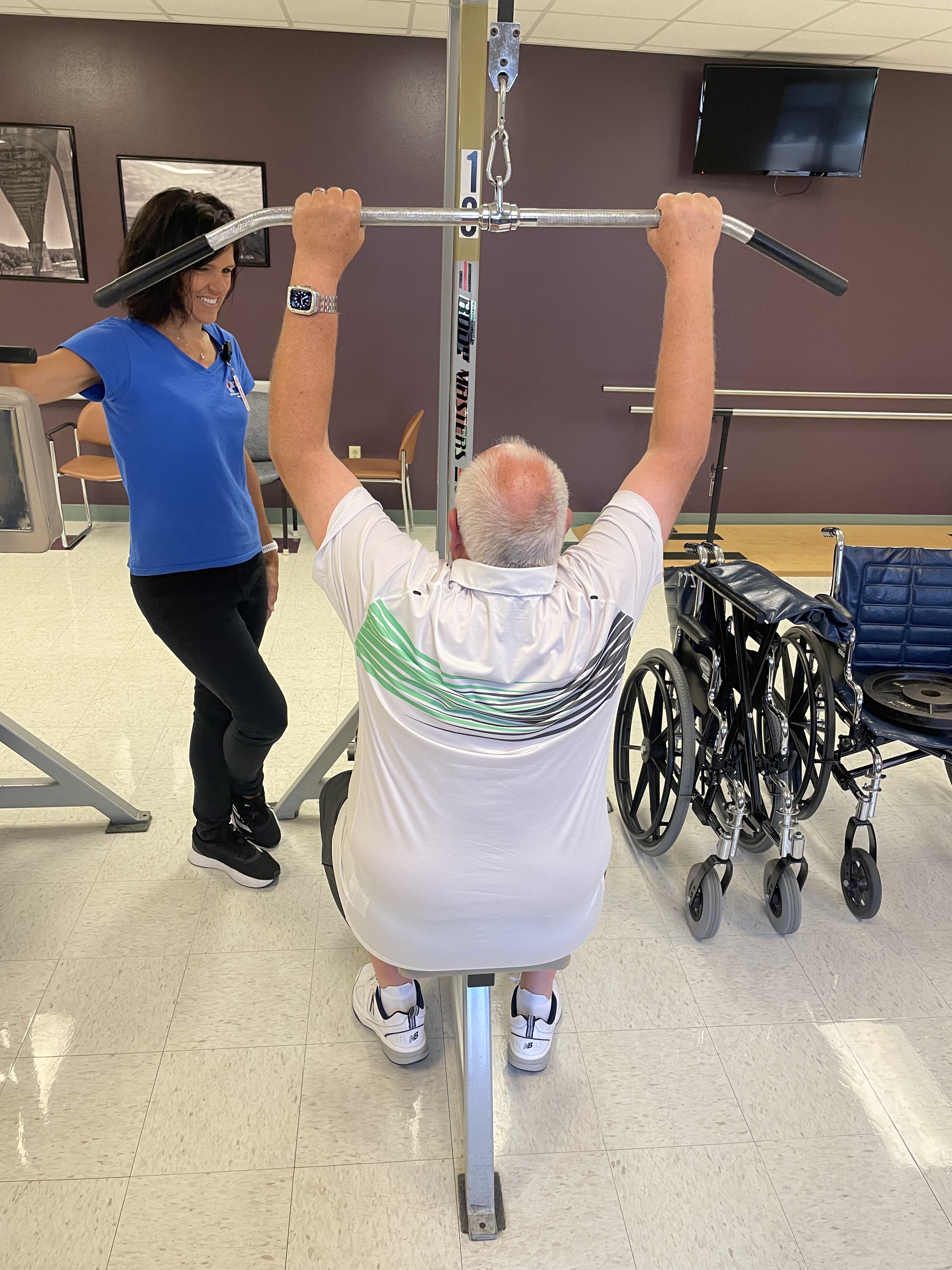 A female therapist helping a patient with a pull-down bar exercise