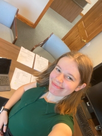 Selfie of Celina from her desk in an oak furniture and decor office environment