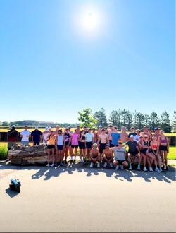 Group photo of dozens of runners along the side of a road