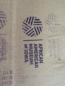 A stamp with the logo for the African American Museum of Iowa stamped on yellowish brown paper