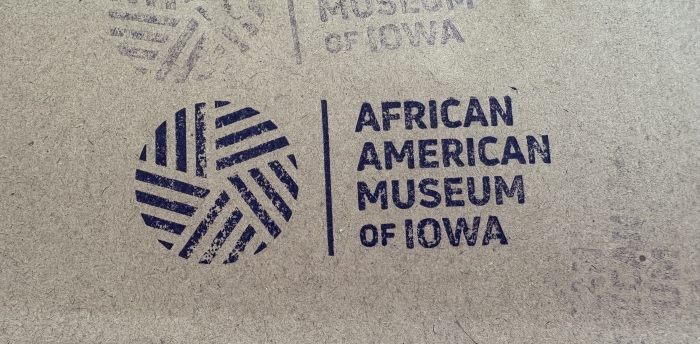 A stamp with the logo for the African American Museum of Iowa stamped on yellowish brown paper