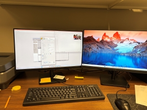 The intern computer desk setup for creating a finding map for the Wynn collection and scanning photos. There are two computer monitors, a keyboard, and mouse.