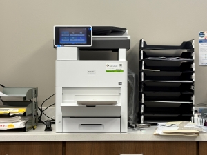 Black copy machine on an office counter next to other filing and office items