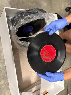 Orion's hand, gloved, holding a thick vinyl record