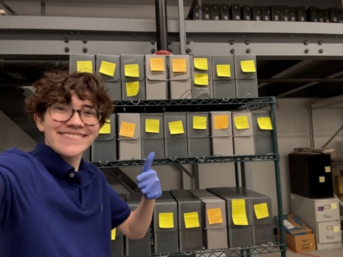 In this selfie, Orion flashes a thumbs up with the finished organized shelves with sticky notes
