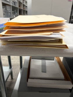 A stack of manilla folders filled with newspapers sits on a table