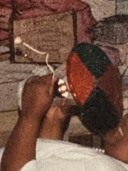 Grainy close-up of a photo in sepia tones of black arms holding some sort of amplifying object that looks a little like a mini phonograph