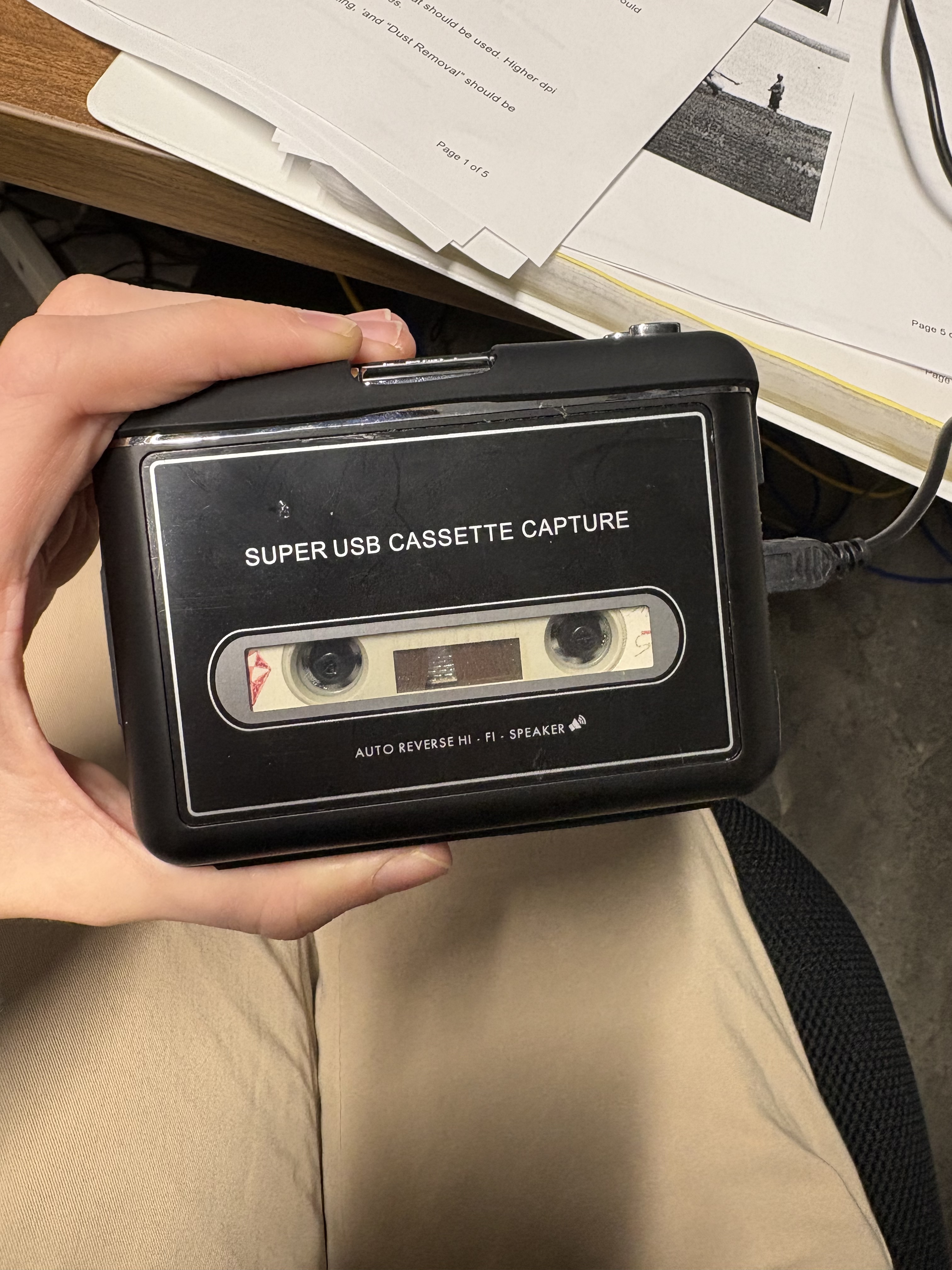 View of a hand holding an unmarked cassette tape