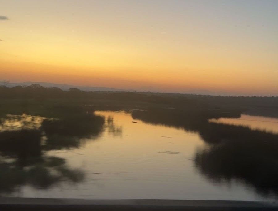 Sunset over one of the reserve habitats in remote South Africa: a blend of blues, yellows, and pinks over water and grasslands