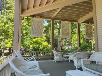 View inside a wrap-around porch with several pieces of white porch chairs