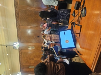 A crowd of diverse people in a courtroom setting. The people are dressed mostly business casual with some closer to formal attire