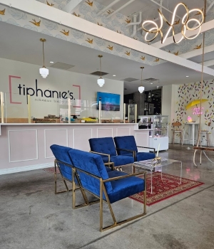 Restaurant seating area (blue furniture) near a counter. "Tiphanie's" is stenciled on the wall behind the counter.